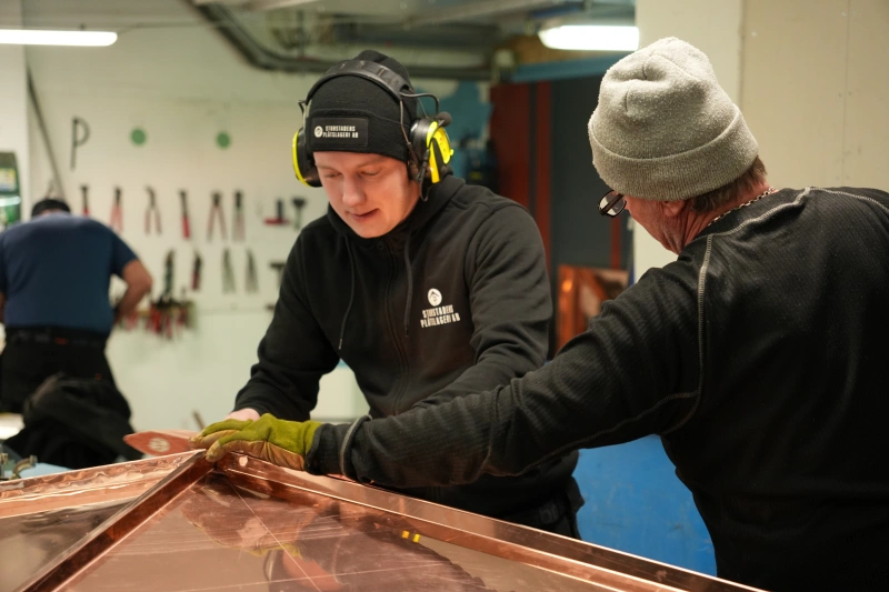Two men working on a sheet metal roof.